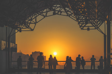 Silhouetted visitors line a waterfront promenade as the sun sets Nov 16 2025のeditorial素材