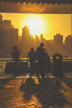 Silhouettes of visitors stand against a golden sunset as a dense city skyline Nov 16 2025のeditorial素材