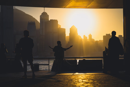 Silhouettes of visitors stand against a golden sunset as a dense city skyline Nov 16 2025のeditorial素材