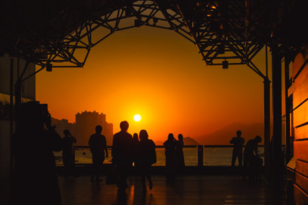 Silhouetted visitors line a waterfront promenade as the sun sets Nov 16 2025のeditorial素材