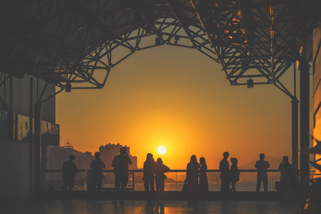 Silhouetted visitors line a waterfront promenade as the sun sets Nov 16 2025のeditorial素材