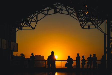 Silhouetted visitors line a waterfront promenade as the sun sets Nov 16 2025のeditorial素材