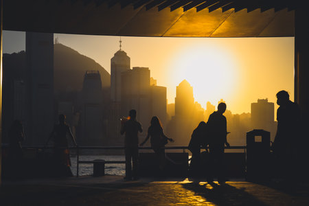 Silhouettes of visitors stand against a golden sunset as a dense city skyline Nov 16 2025のeditorial素材