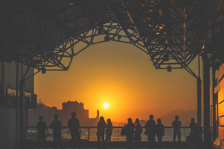 Silhouetted visitors line a waterfront promenade as the sun sets Nov 16 2025のeditorial素材
