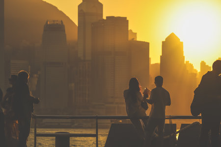 Silhouetted figures stand on a balcony as a warm sunset bathes Nov 16 2025のeditorial素材