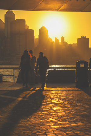 Silhouettes of visitors stand against a golden sunset as a dense city skyline Nov 16 2025のeditorial素材