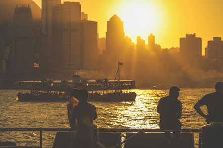 Two silhouetted figures by a railing overlook a golden sunset Nov 16 2025のeditorial素材