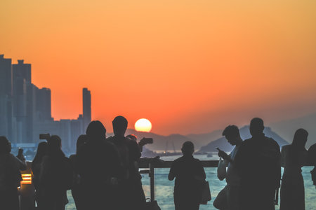 Silhouetted group stands on a sunlit balcony as the city skyline glows Nov 16 2025のeditorial素材