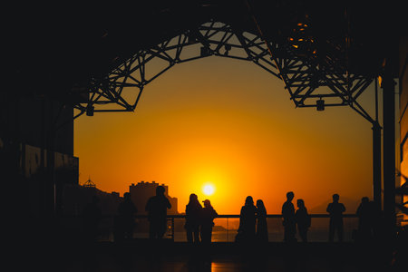 Silhouetted visitors line a waterfront promenade as the sun sets Nov 16 2025のeditorial素材