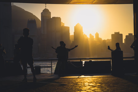 Silhouettes of visitors stand against a golden sunset as a dense city skyline Nov 16 2025のeditorial素材