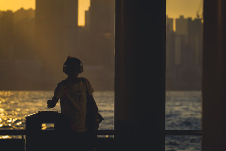 Silhouetted figures stand along a railing at sunset, overlooking a shimmering Nov 16 2025のeditorial素材