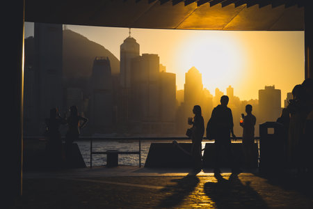 figures stand by a glass railing as a brilliant orange sunset Nov 16 2025のeditorial素材