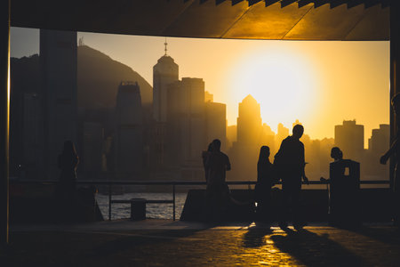 figures stand by a glass railing as a brilliant orange sunset Nov 16 2025のeditorial素材