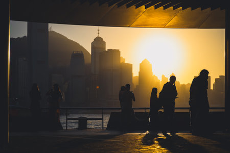 Silhouettes of visitors stand against a golden sunset as a dense city skyline Nov 16 2025のeditorial素材