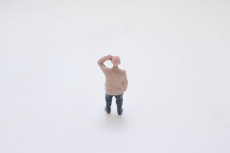 A small plastic man figure stands on a white surface, wearing jeans.の写真素材