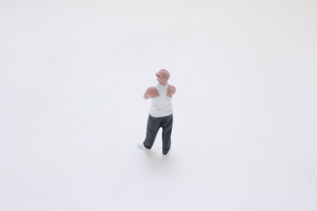 A small male figurine stands on a white surface, wearing aの写真素材