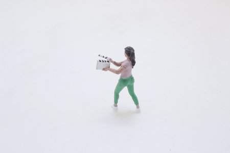 stands on a clean white background, holding a clapperboard aの写真素材