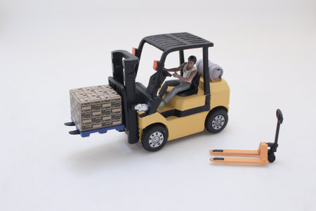 toy forklift with a driver moves a boxed pallet in a miniature wの写真素材