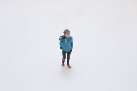 description A small plastic figurine of a man in a blue sweater with a backpackの写真素材