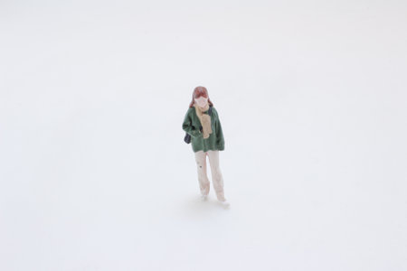 A tiny female figurine stands on a clean white surface,の写真素材