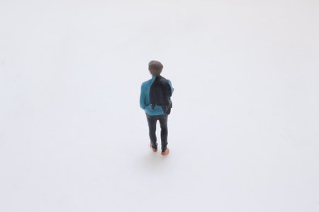 description A small plastic figurine of a man in a blue sweater with a backpackの写真素材