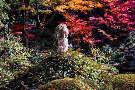 A serene garden scene features a mossy stone statue encircled Nov 23 2025のeditorial素材