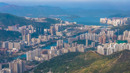 Urban skyline stretches across valley beneath surrounding green mountains Jan 25 2026