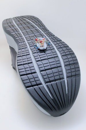 Tiny rafting team rows vigorously across textured sneaker surfaceの写真素材