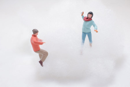 Tiny winter figurines throw snowballs amid fluffy artificial snowの写真素材