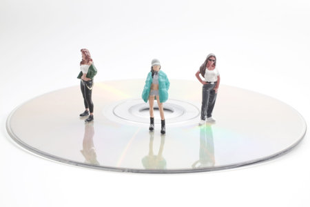 Tiny figurines stand stylishly arranged across smooth CD surfaceの写真素材