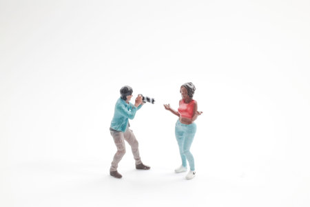 Tiny figurines recreate photo shoot scene on bright backdropの写真素材