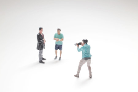 Tiny figurines recreate lively photo shoot moment on white backdropの写真素材