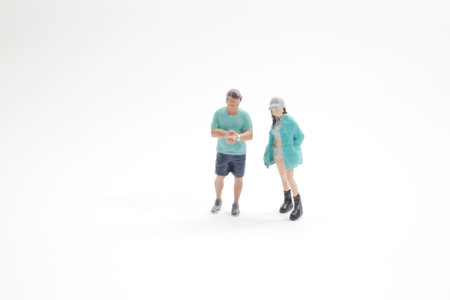 Tiny figurines pose together on clean minimal studio surfaceの写真素材