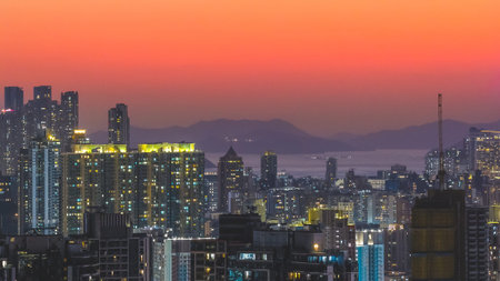 Tall illuminated towers rise against vivid orange dusk horizon Feb 15 2026のeditorial素材