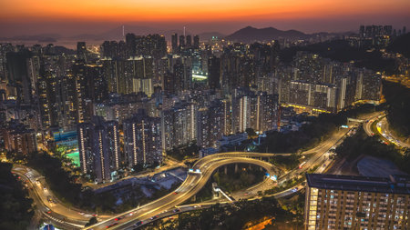 Evening city lights illuminate dense highrise buildings beside highway Feb 13 2026のeditorial素材