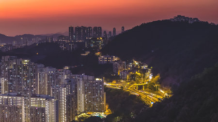 Evening city lights illuminate dense highrise buildings beside highway Feb 13 2026のeditorial素材