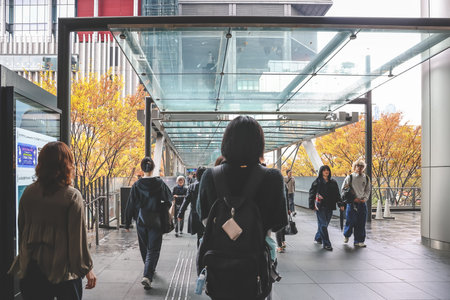 Pedestrian bridge near office towers with autumn foliage Nov 25 2025