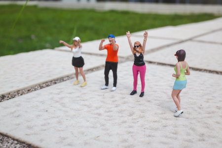 Tiny figurines pose in lively stances across bright open walkwayの写真素材