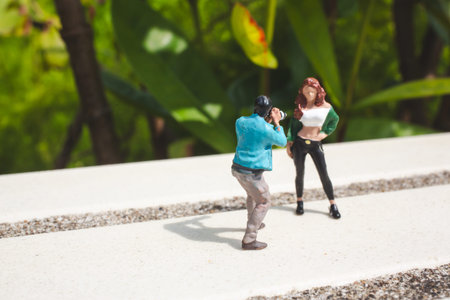 Tiny figurines depict photo shoot scene on sunlit outdoor platform