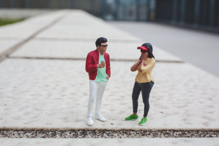 Tiny figurines pose casually with relaxed gestures on concrete surfaceの写真素材