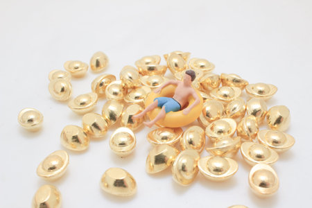 Tiny figurine rests in inflatable ring atop shiny gold pieces
