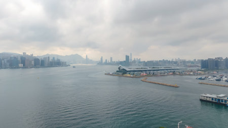 March 27 2026 towers emerge faintly beyond calm overcast harbour waters, HK