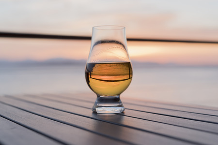 Old fashioned whiskey glass outside at sunsetの写真素材