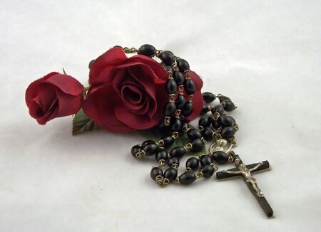 a rosary cross and beads with red silk rosesの写真素材