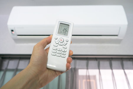 Man's hand using remote control open The air conditioner is cooled to 25 degrees Celsius in his bedroom. Health concepts and energy savingsの写真素材