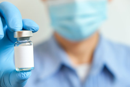 doctor's hand holds a syringe and a blue vaccine bottle at the hospital. Health and medical concepts.の写真素材