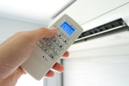 Man's hand using remote control open The air conditioner is cooled to 25 degrees Celsius in his bedroom. Health concepts and energy savingsの写真素材