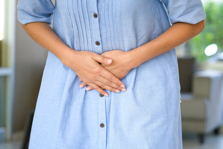 A woman holding her stomach with her hands, she has abdominal pain and abdominal pain. From stomach ailments and menstrual crampsの写真素材