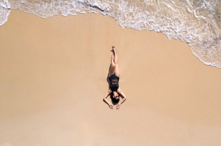 Aerial view, women lounging, sunbathing on the beach and beautiful blue water waves on the island of Thailand.の写真素材