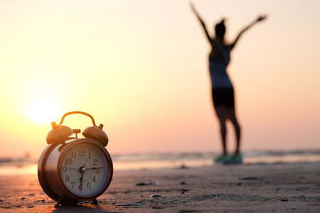 Morning of a new day, alarm clock  woman playing yoga and stretching muscles on the beach sunlight in morning. Health concept.の写真素材
